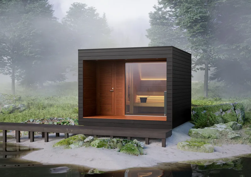A dark timber sauna glowing in a misted forest